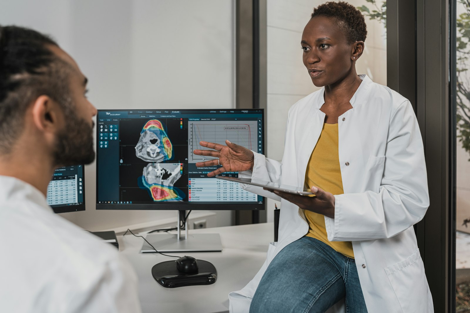 Two clinicians reviewing medical scan images on desktop monitors