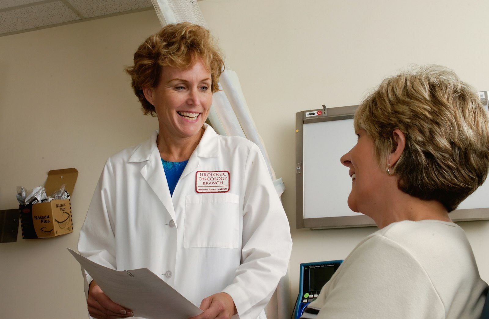 A clinician in a white coat discussing a results folder with a patient