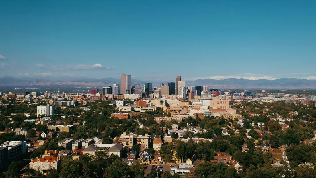 The downtown Denver skyline with the Rocky Mountains behind it